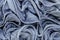 Background in the form of material made of gray leather with a blue tint with numerous wavy folds over the entire area of â€‹â€‹