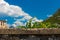 Background image. In the background is a blurred landscape of tourists, an old building, mountains and a blue sky