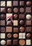 Background of luxury chocolates in a box, in different flavours of dark, milk, white and caramel