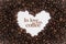 Background made of coffee beans in a heart shape with message `In love with coffee`