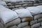 Background of many dirty sand bags for flood defense. Protective sandbag barricade for military use. Handsome tactical bunker