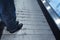 Background men wearing jeans and black leather boots. Stand up the escalator, close-up the legs.