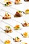 Background of mixed canapes on metal spoons. White background