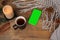 Background with mug of tea, smart phone with blank green screen, candles, knitted shawl with fringe, coniferous branches and