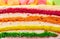 Background of multicolor four layer cake with colored marshmallow on the top. Close up. Rainbow cake texture