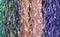 Background of multicolored ribbon streamers hanging vertically including green purple pink white and yellow