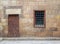 Background of old stone bricks wall with grunge wooden closed door and window with iron grid