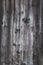 Background from old worn darkened from time to time gray knotty vertical wooden plank close up