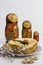 Background with pancakes, wooden dolls matryoshka, sushki and spoon with red caviar on white for Maslenitsa festival.