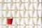 Background pattern of white paper cups with red cup in the middle