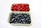 Background of raspberry and blueberry in packing containers, cardboard boxes with berries, red and blue fruit in package