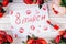 Background of red roses, lipstick and prints of women`s lips on a wooden table for International Women`s Day