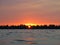 Background of red sunset at water with skyline of trees