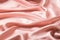 Background of satin pink cloth draped in waves. Copy space.