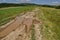 Background of sky, clouds, field, road with puddle after flood rain and forest