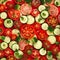 Background of slices of ripe appetizing tomatoes and cucumbers, red green food background,