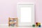 Background template, white vertical picture frame with matte and toddlers toys in front of pink wall