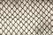 Background and texture for design. Abstract chain link fence texture against grungy gray color wall.