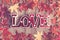 Background texture of old wooden table, yellow autumnal fallen maple leaves, lamp in form of red letters love
