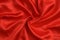 Background twisted red satin fabric with folds