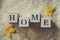 Background with warm sweaters and the inscription HOME. Pile of knitted clothes with autumn leaves, knitwear, Autumn concept.