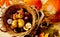 Background with wicker basket full of chestnuts in shell, framed with fall leaves and small red hokkaido pumpkin