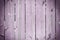 Background of wooden strips dyed in purple. Fence of flat boards.