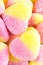 Background of yellow and pink fruit candy in shape of heart, close up