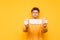 Background. Young man in a yellow sweater holding a gauze medical mask on a yellow background, focus on personal protective