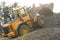 backhoe dumping rubble onto a steep pile of stones