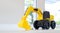 Backhoe loader, yellow construction toy vehicle with articulated parts built with sturdy plastic is placed on a table