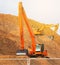 Backhoe standing on pile of woodchips during pile making work