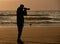 Backlight silhouette of photographer standing upon the foreshore