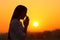 Backlight of a woman praying at sunset