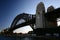 Backlighted silhouette of historic Sydney Harbor Bridge in twilight. Backlit heritage steel truss arch bridge spanning over water