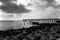 Backlit, black and white silhouette of a man standing on a fishing pier.