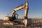 Backlit excavator on an industrial site against the background of the evening sky. Construction machinery for earthworks