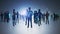 Backlit group of businesspeople standing on light background with glowing digital arrows hologram. Teamwork and technology concept