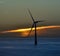 Backlit offshore turbine at sunrise