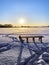 Backlit photo of a sledge standing on a snowy plain in the light of the setting sun