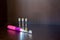 A backlit pink electric battery-powered toothbrush with three interchangeable nozzles lies on a shelf