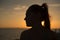 Backlit profile of a pretty woman looking at a beautiful sunset by the sea