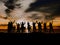 A backlit shot of a group of cycling friends standing in line at sunset