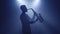 Backlit silhouette of saxophonist man with saxophone in dark nightclub studio and start playing sax