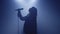 Backlit silhouette of singer vocalist girl standing in dark nightclub disco studio and start singing