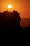 backlit silhouettes of people enjoying a sunset from a cliff overlooking the sea