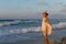Backlit woman feeling free and happy, breathing clean fresh ocean air on a sandy beach in summer at dusk