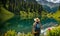 Backpack-adorned girl standing at edge of serene mountain lake