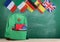 backpack, flags of Spain, France, Great Britain and other countries and school supplies on the background of the blackboard