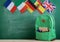 backpack, flags of Spain, France, Great Britain and other countries and school supplies on the background of the blackboard